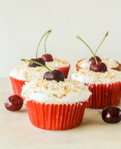 Mini coconut and fresh cherry cakes with whipped cream and toasted coconut topping