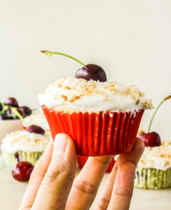 Mini coconut and fresh cherry cakes with whipped cream and toasted coconut topping