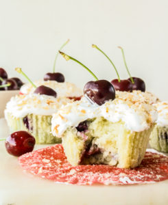 Mini coconut and fresh cherry cakes with whipped cream and toasted coconut topping