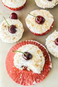 Mini coconut and fresh cherry cakes with whipped cream and toasted coconut topping
