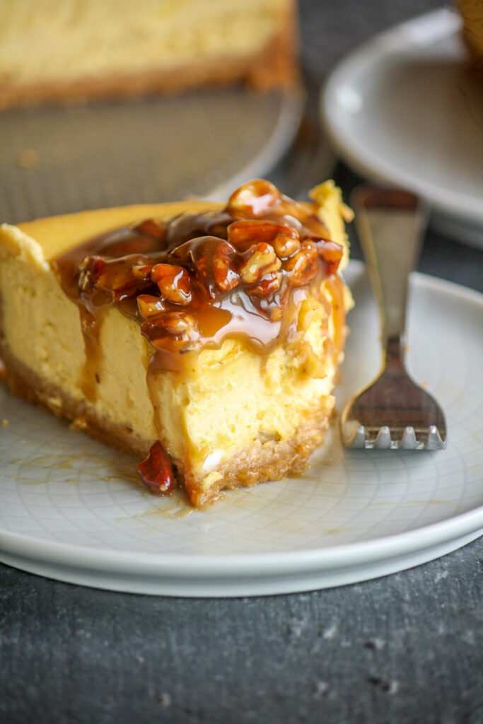 Creamy baked cheesecake with homemade pumpkin puree with a roasted pecan and caramel topping