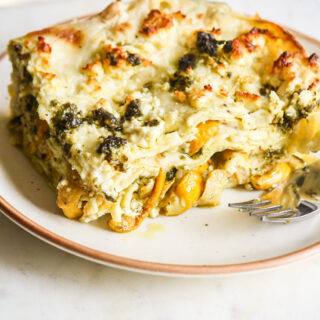 Roasted zucchini and pesto lasagna layered with cream cheese sauce and topped with feta