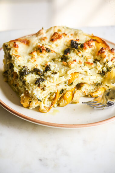 Roasted zucchini and pesto lasagna layered with cream cheese sauce and topped with feta