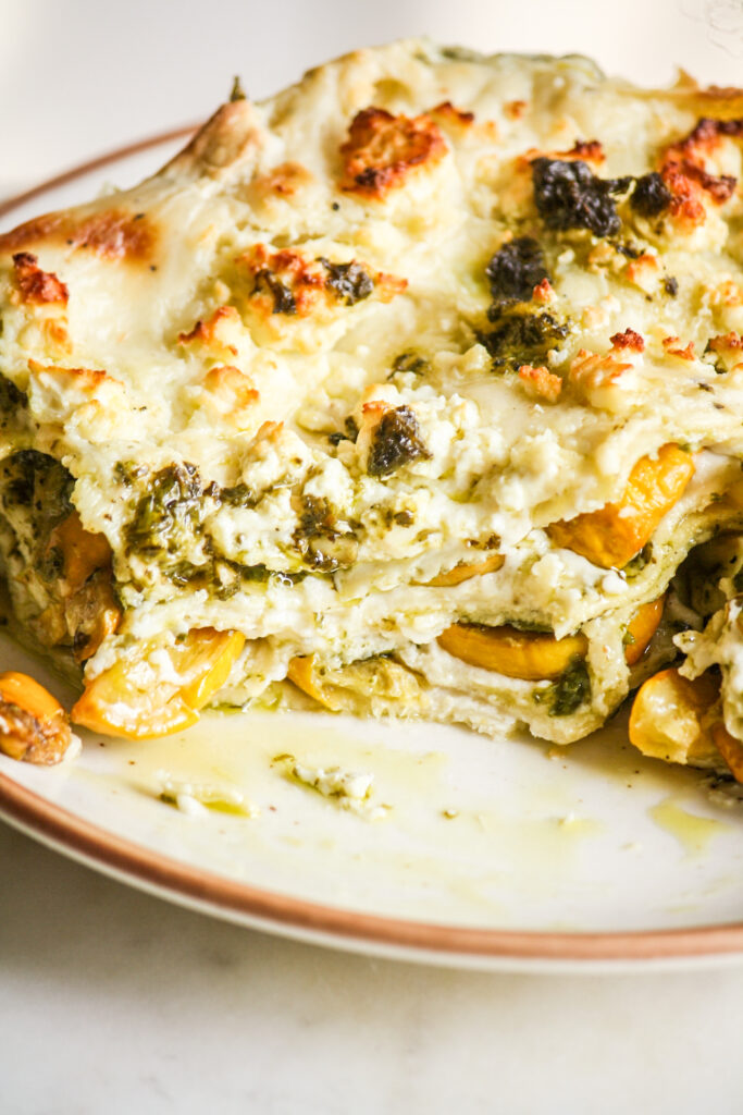 Roasted zucchini and pesto lasagna layered with cream cheese sauce and topped with feta