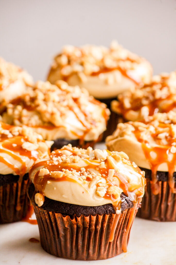 Dark chocolate cupcakes with peanut butter frosting, salted caramel and chopped roasted peanuts